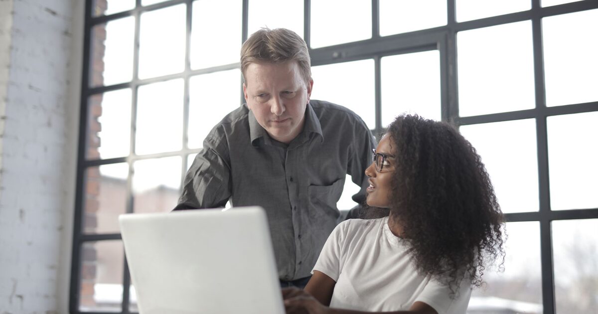 Coach guiding a candidate working on a laptop