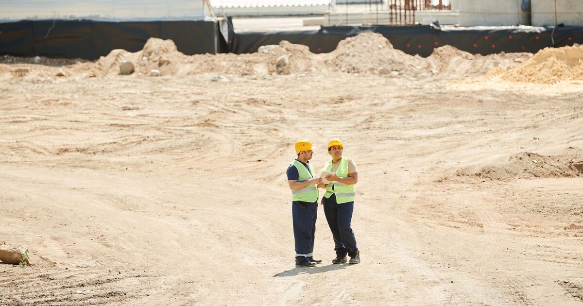 International construction workers reviewing plans on a building site
